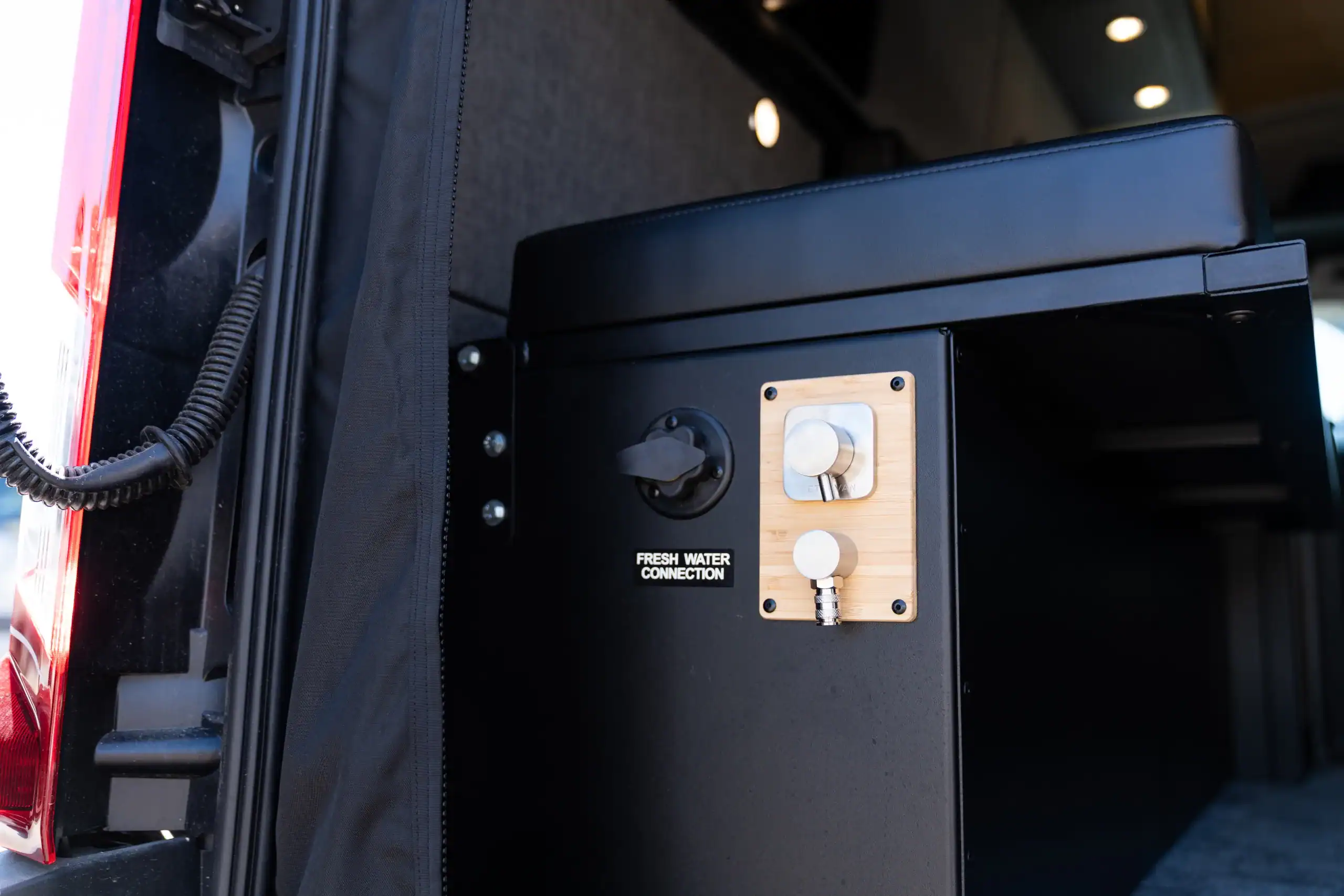 Fresh water connection panel inside the van for plumbing and water supply.