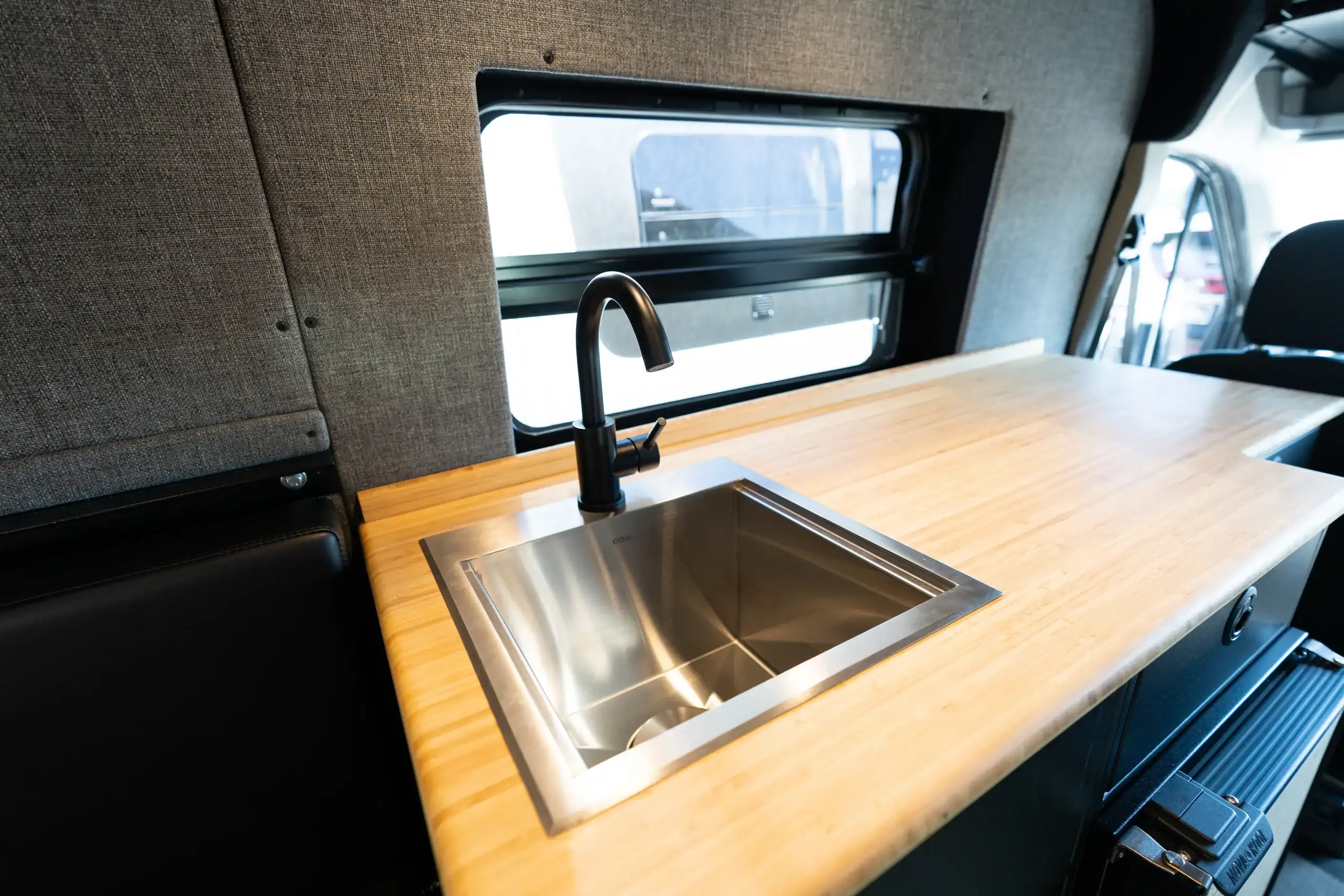 Interior view of van with wooden countertop and stainless steel sink.
