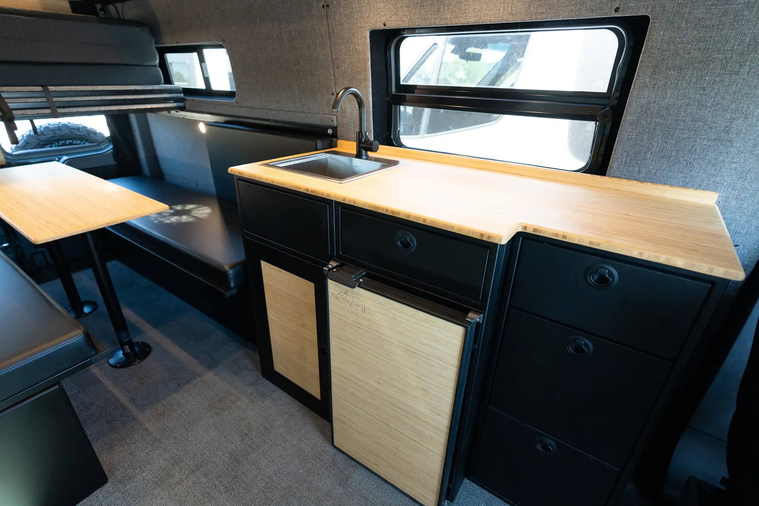 Modern van interior with kitchenette and seating for travel and camping.