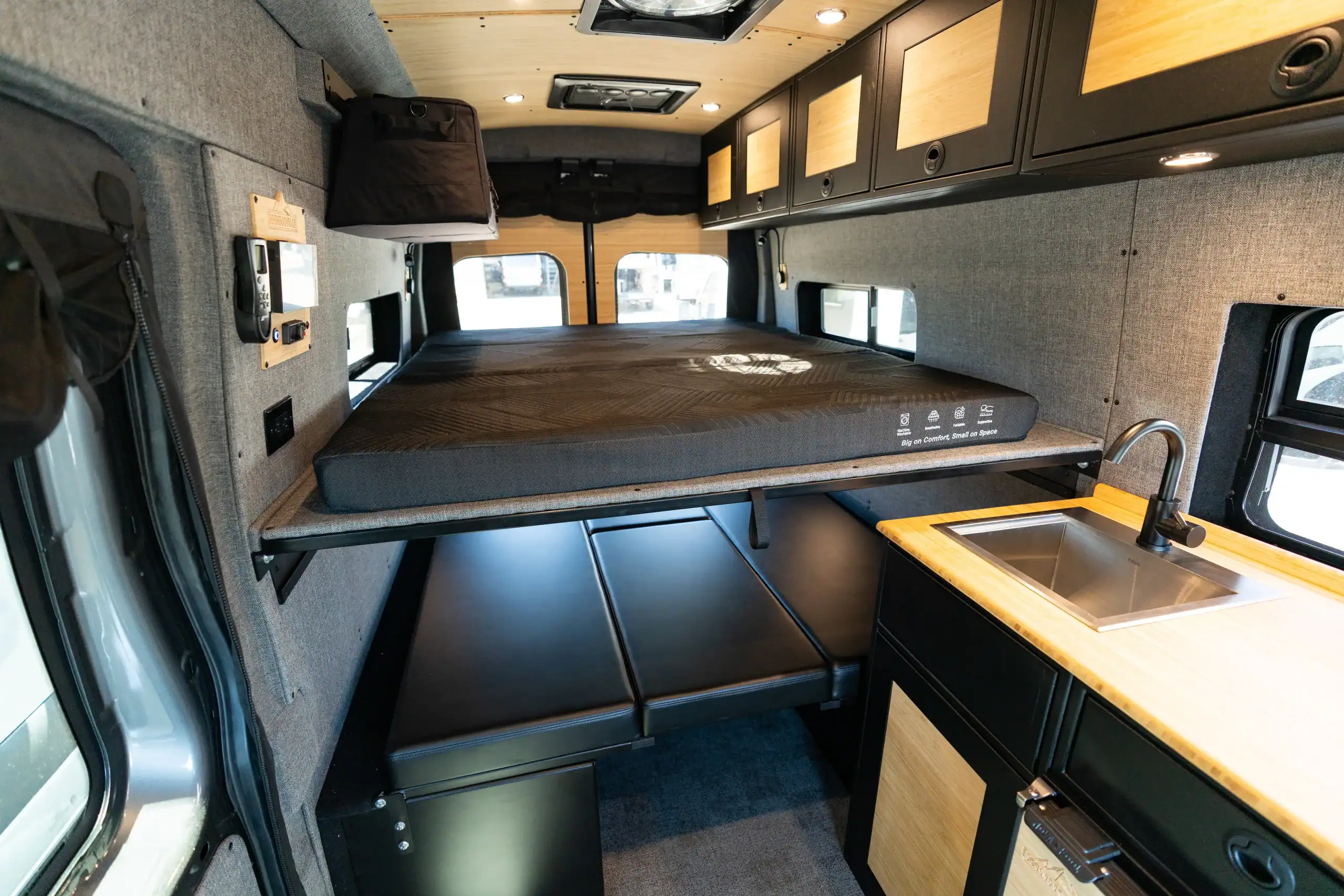 Interior view of the 2026 Switchback S4 Transit van with sleeping area and kitchenette.