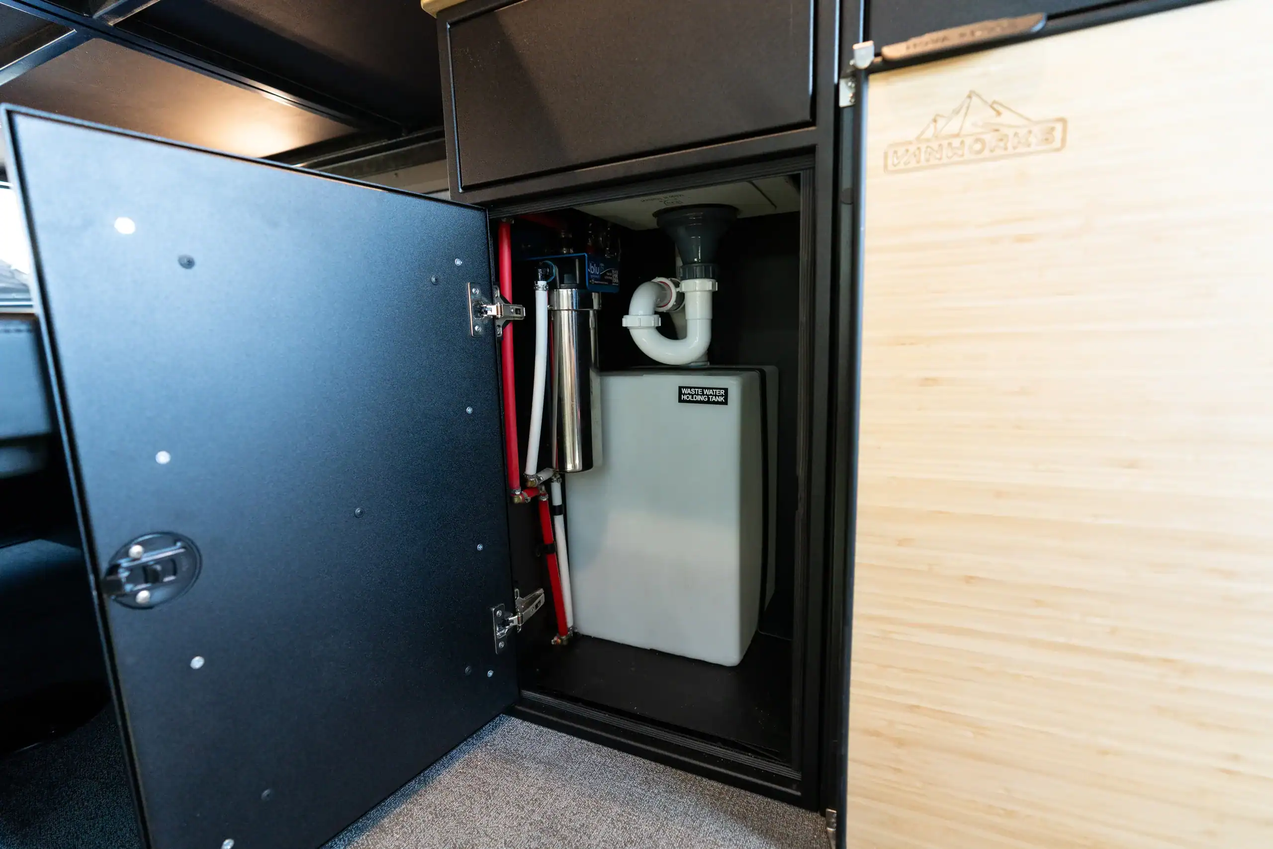 Interior view of van conversion with water system components.