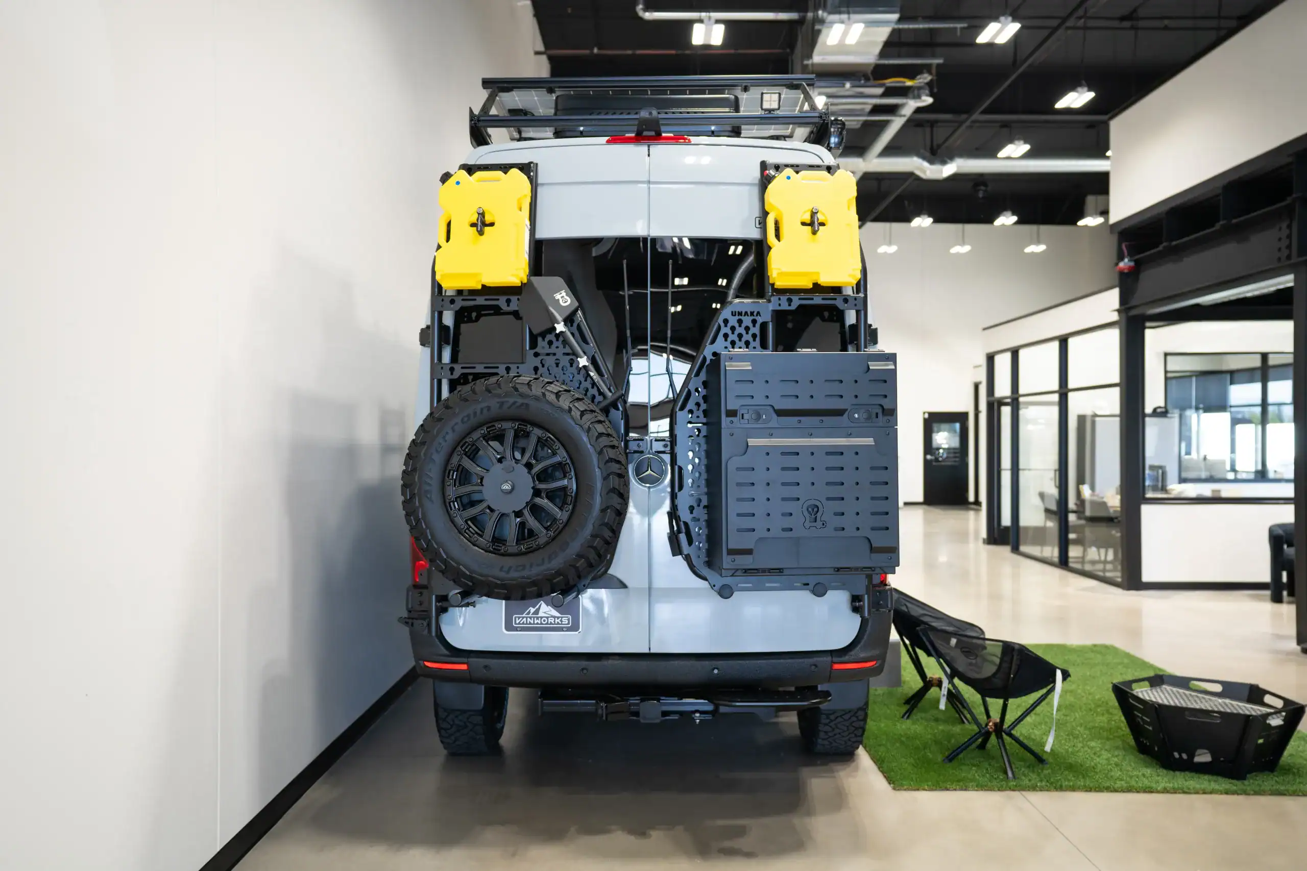 Rear view of a van with custom storage and spare tire in a showroom.