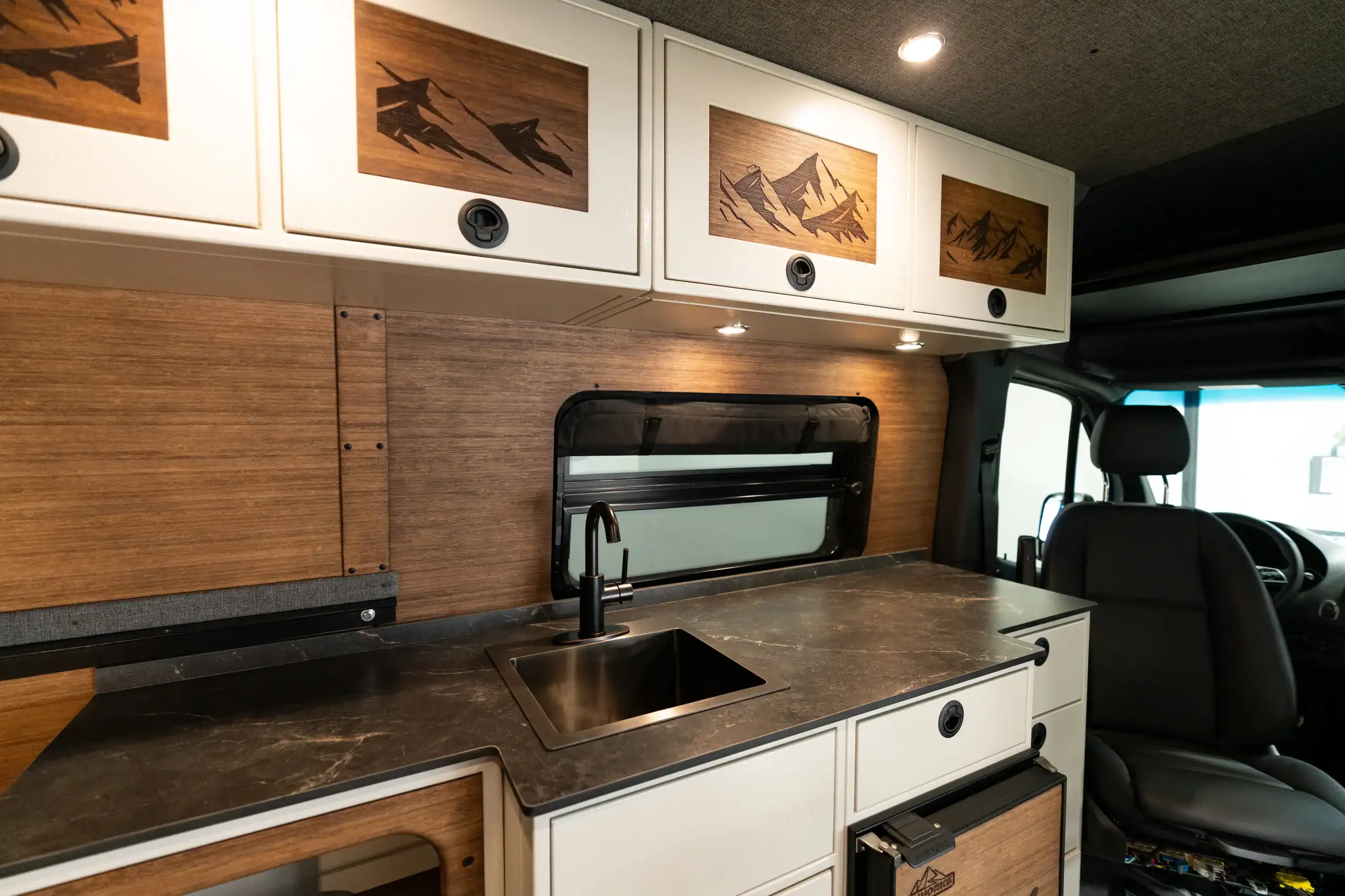 Interior view of Vanworks Switchback Sprinter with custom cabinetry and wood accents.