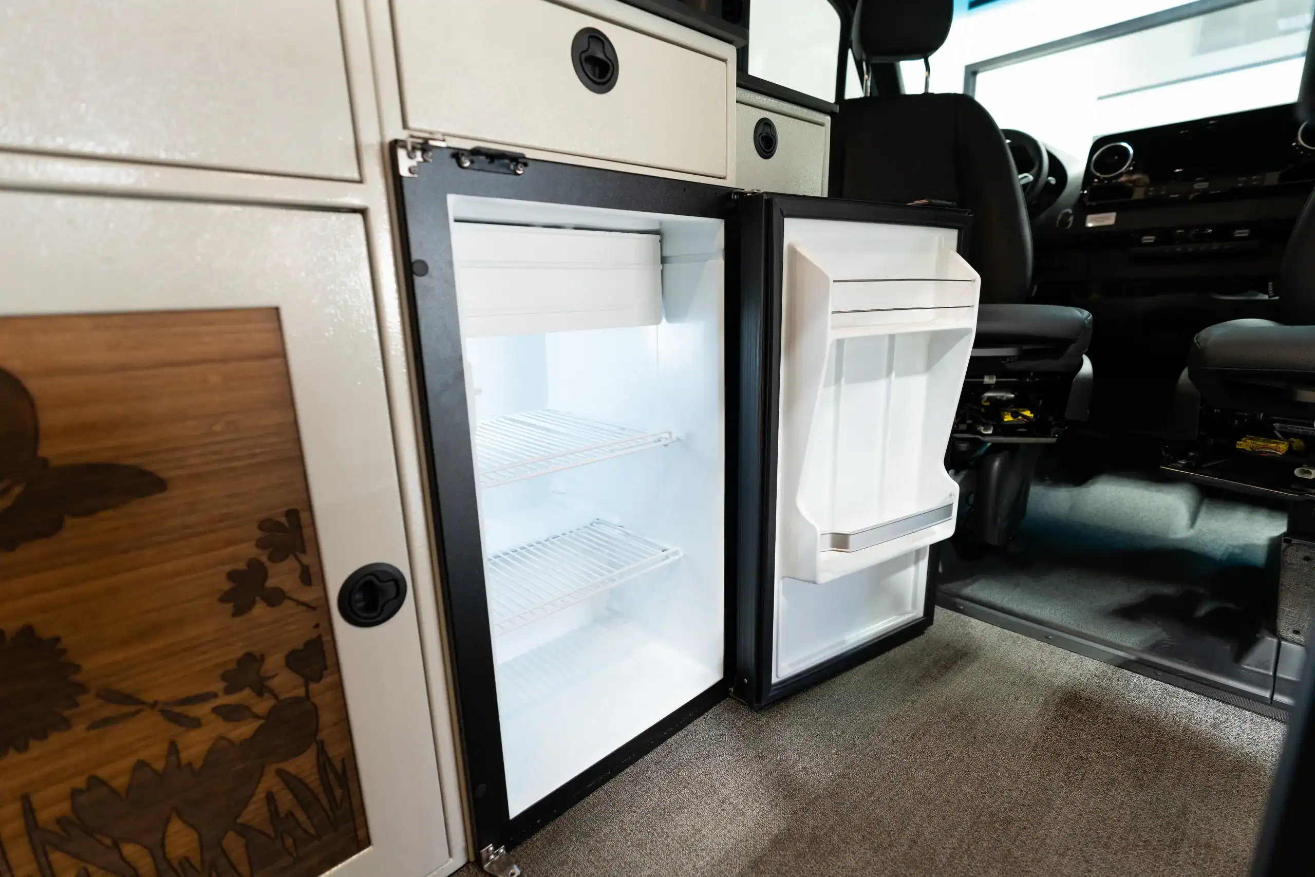 Interior view of a compact refrigerator inside a van conversion.