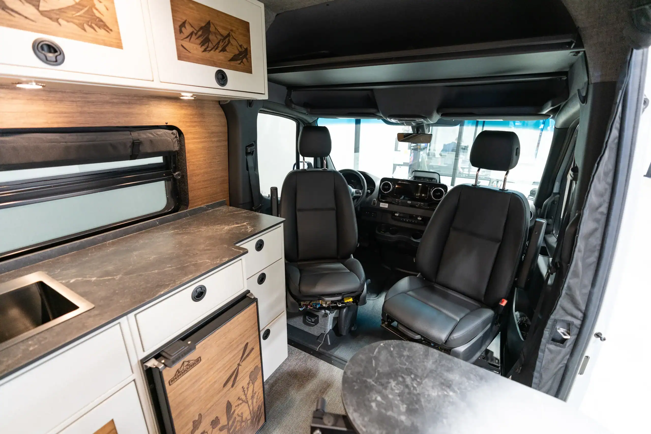 Interior view of a Vanworks Sprinter camper van with kitchen and seating area.