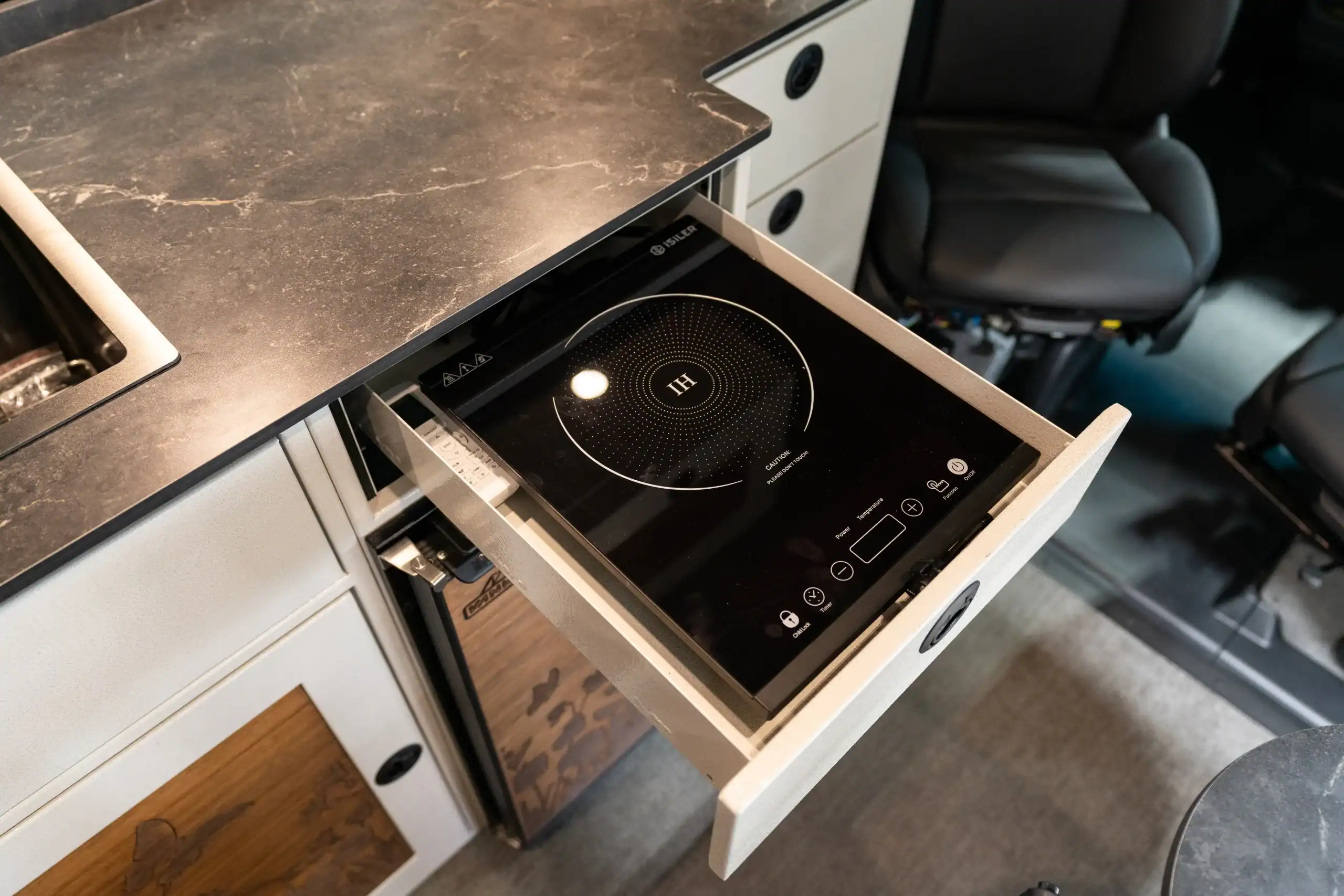 Built-in induction cooktop in a Vanworks camper van kitchen.